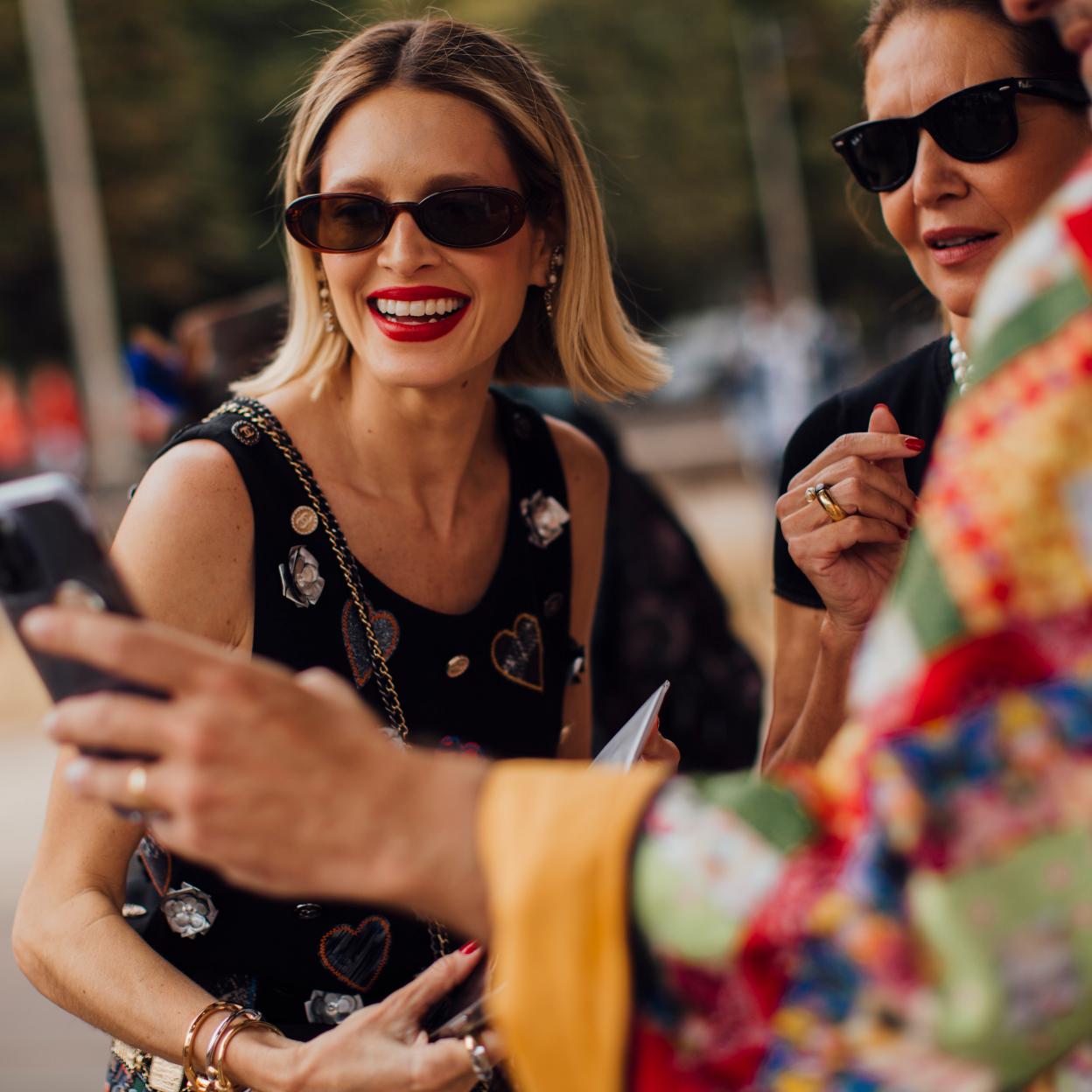 Unas amigas compartiendo sus lista de básicos de verano beauty en el móvil.