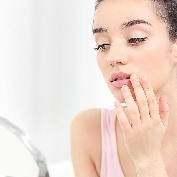 Mujer aplicando tratamiento para labios secos por el sol