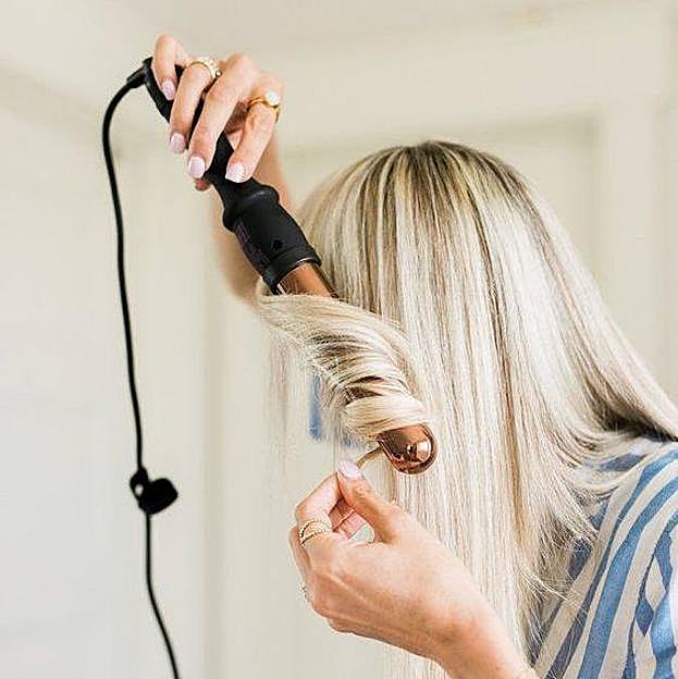 Mujer ondulado el pelo con tenacillas