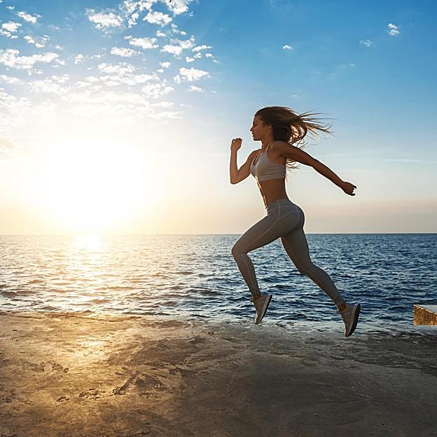 Mujer practicando running en la playa. 