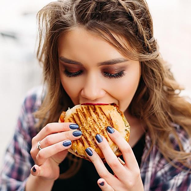 Mujer comiendo una hamburguesa. 