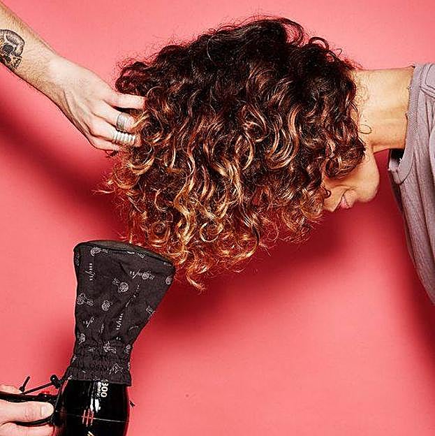 Mujer con pelo rizado usando secador con difusor