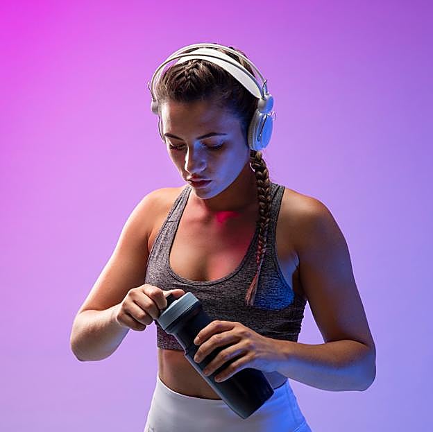 Mujer con auriculares y botella de agua a punto de iniciar su rutina de entrenamiento. 