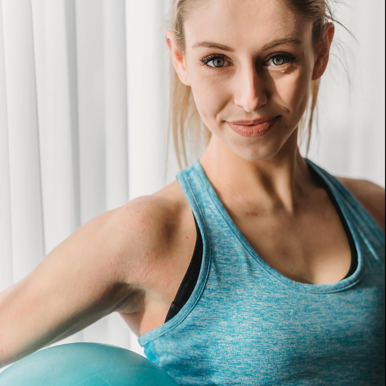Mujer con ropa deportiva y una fitball preparada para hacer ejercicio. 