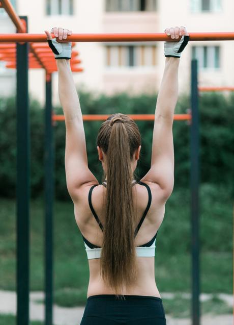 Imagen - Mujer realizando dominadas al aire libre. / Imagen de freepic.diller en Freepik. 