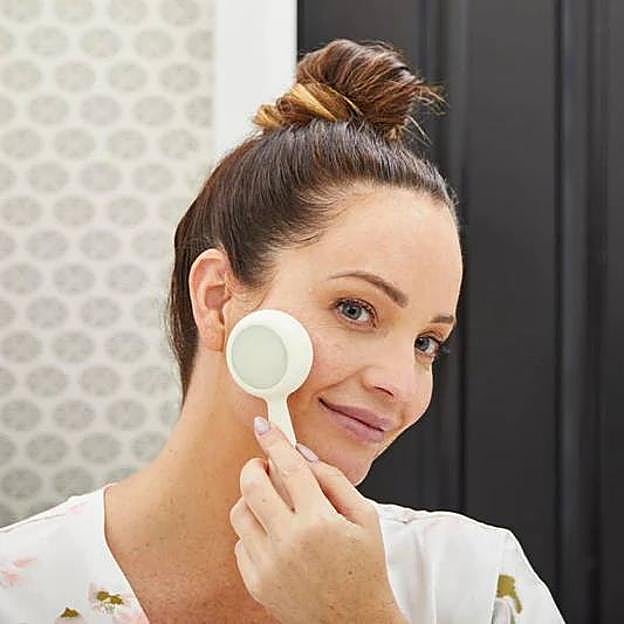 Mujer usando cepillo de limpieza facial