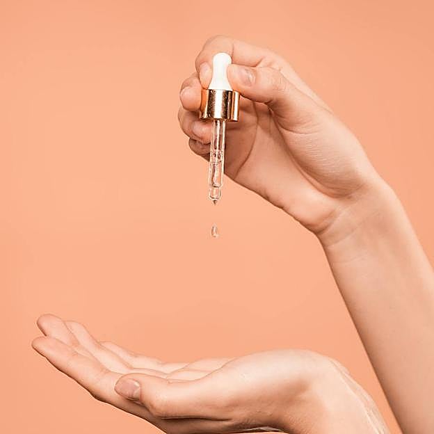 Mujer con sérum facial en las manos