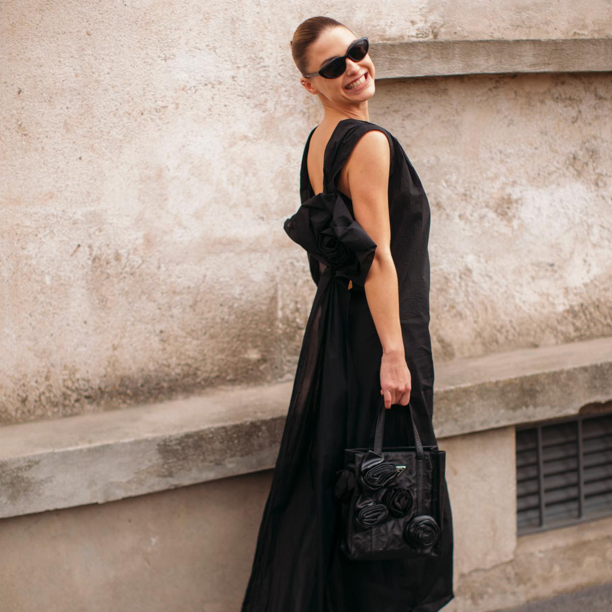 Una modelo con un vestido negro con lazo.