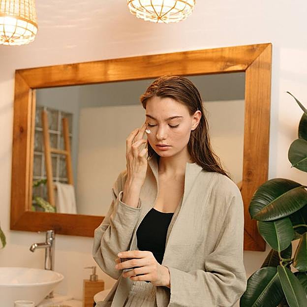 Mujer utilizando crema para eliminar las líneas de expresión de los ojos