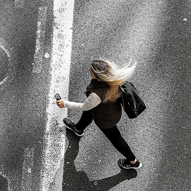 Mujer vista desde arriba caminando por una carretera. 