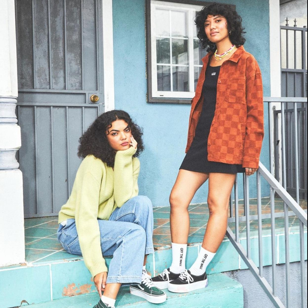 Dos modelos sentadas en unas escaleras de entrada a una casa. 