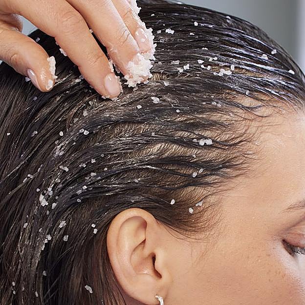 Una mujer exfoliándose el cabello.