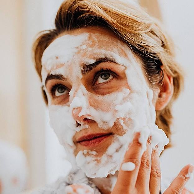 Mujer usando espumas limpiadoras sobre el rostro