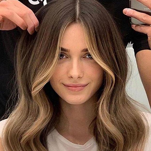 Modelo con pelo rubio oscuro iluminado por mechas money piece