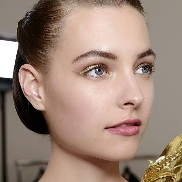 Modelo con maquillaje de ojos iluminador con eyeliner dorado