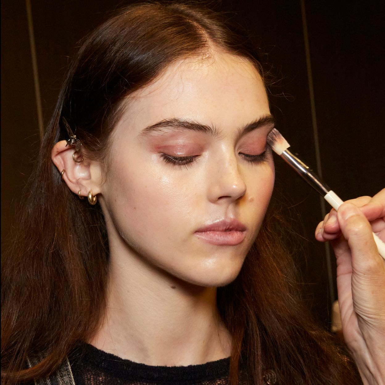 Una modelo aplicándose sombra de ojos.