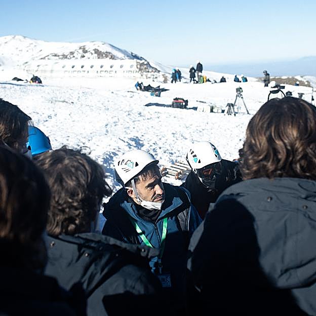 En el centro, Juan Antonio Bayona, en un momento del rodaje de La sociedad de la Nieve en Sierra Nevada, con la réplica del avión estrellado al fondo.