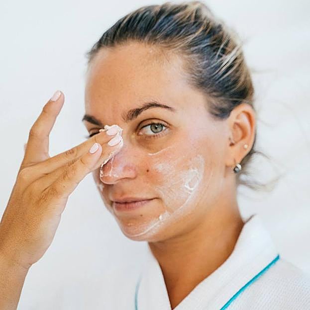 Mujer aplicando crema en la cara