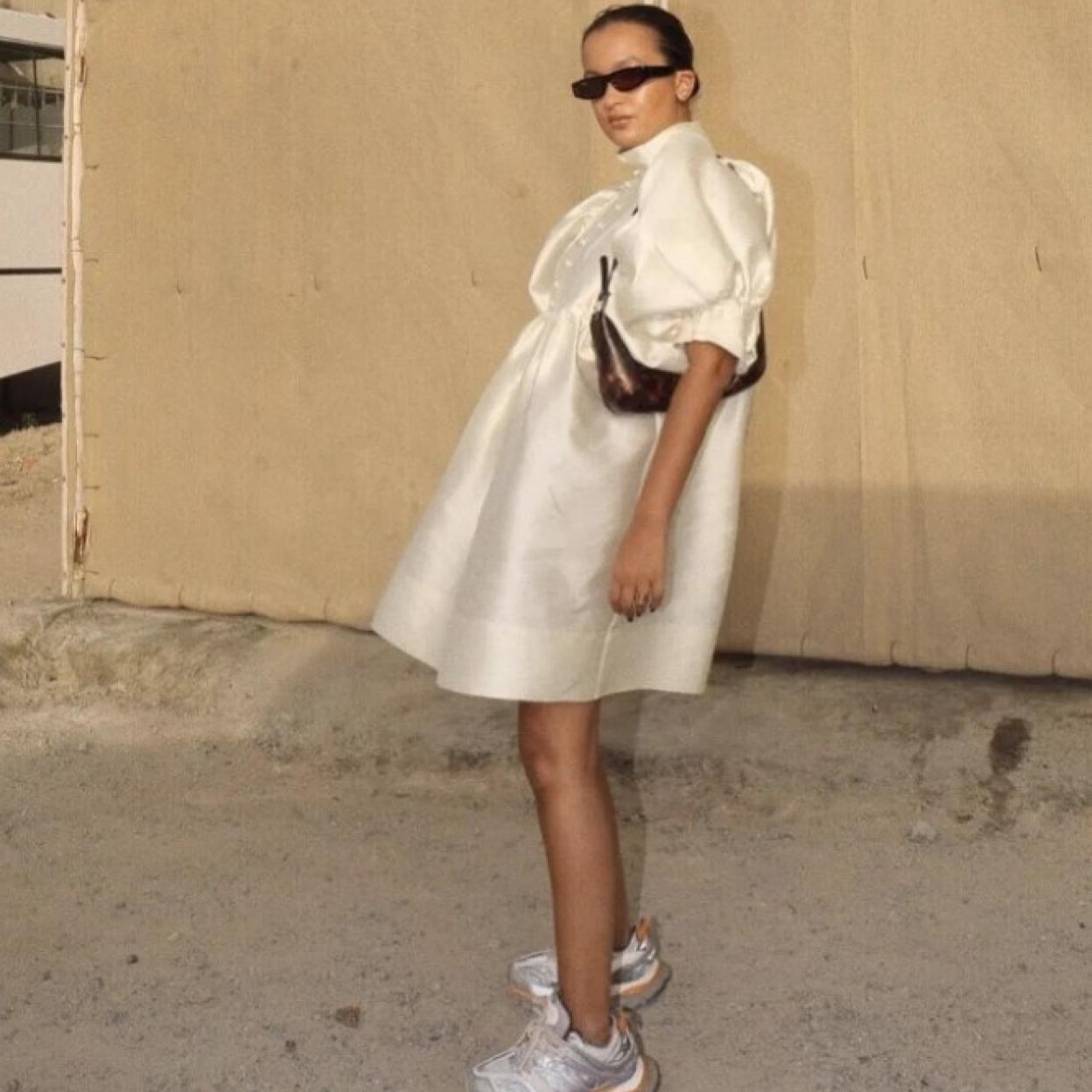 La influencer Oumayma Elboumeshouli con un vestido blanco y zapatillas