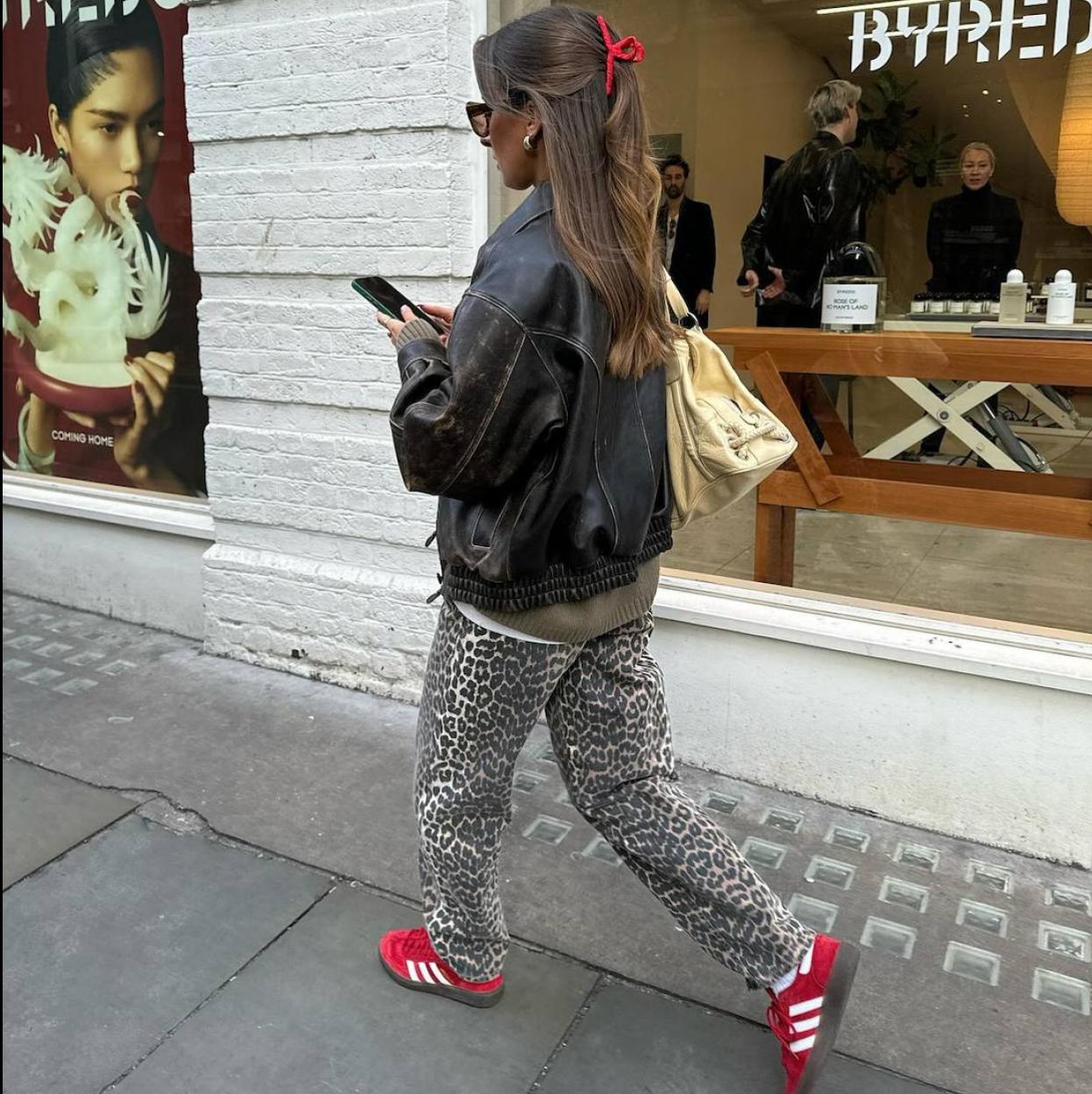 Influencer con look de pantalones de leopardo y zapatillas rojas