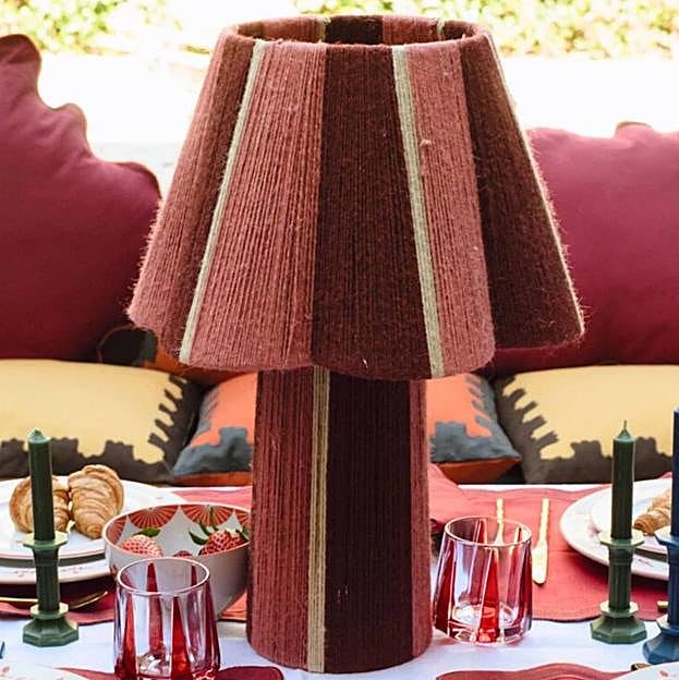 Imagen principal - La lámpara yute floral cuesta 180 euros; los cojines de terciopelo grandes, 75 euros; y la bandeja dorada hecha a mano, 150 euros.