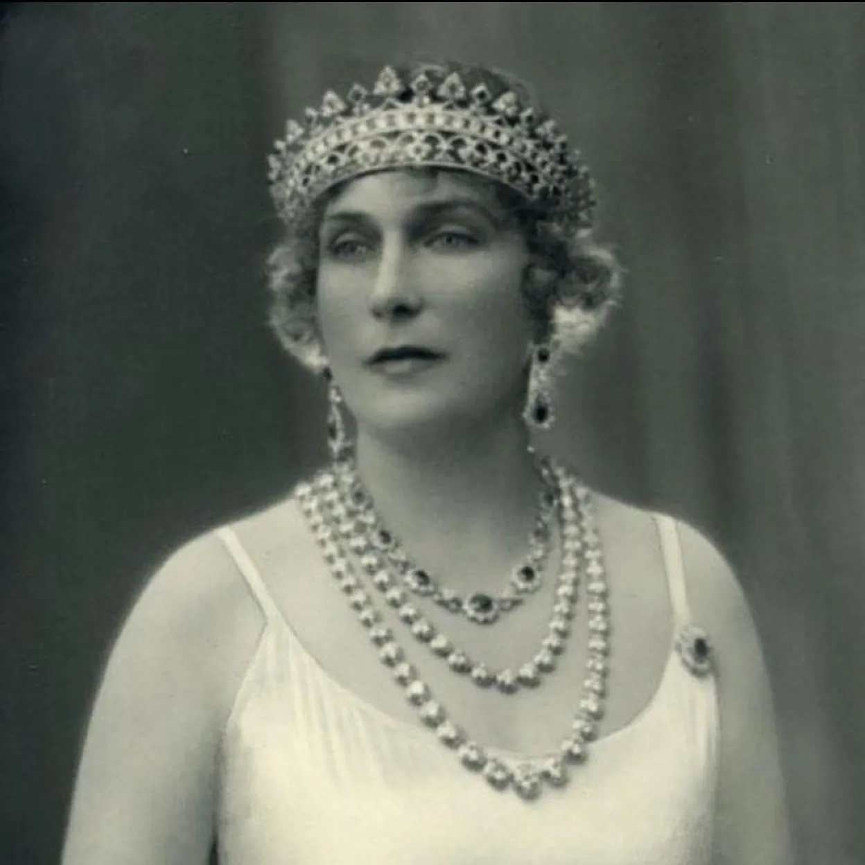 Victoria Eugenia con vestido de tirantes y joyas.