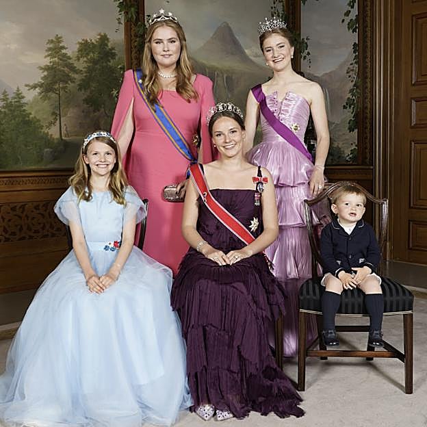 Sentada y con vestido color berejena, Ingrid de Noruega, en su 18 cumpleaños. De pie, Amalia de Holanda y Elisabeth de Bélgica. 