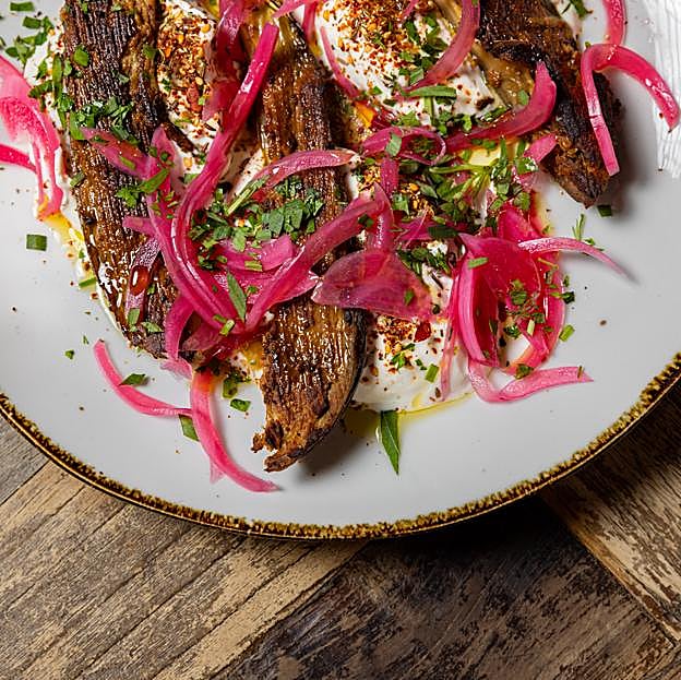 La exquisita berenjena rustida con tahini, labhné de hierbas, encurtido de cebolla roja y sésamo del restaurante libanés Aredna. DR