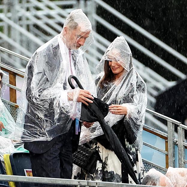 Los reyes Felipe y Letizia, luchando con chubasqueros y paraguas bajo la lluvia de París, en la inauguración de los Juegos Olímpicos. 