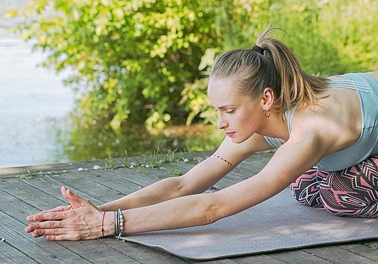 Mujer practicando yoga sobre esterilla.
