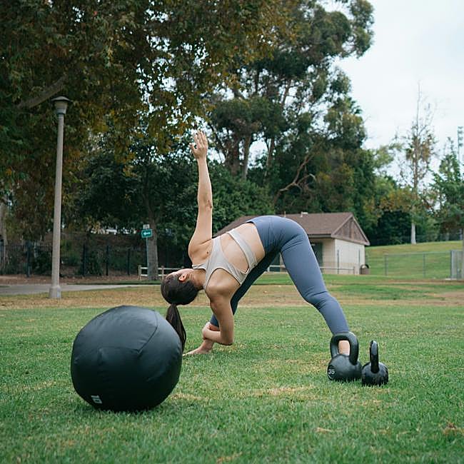 Mujer haciendo ejercicio con pelota y mancuernas.
