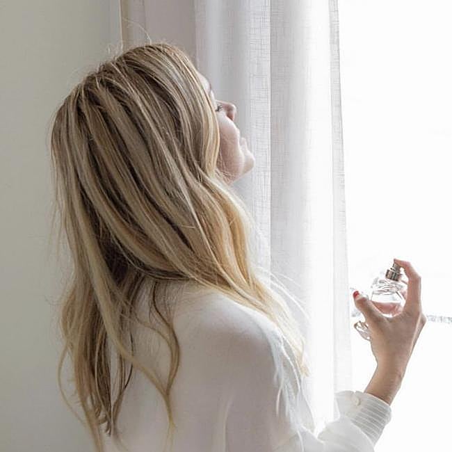 Mujer poniéndose perfume.