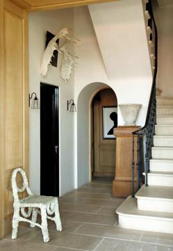 Imagen secundaria 2 - Arriba, la habitación principal de la casa, con cortinas que cubren las paredes del techo al suelo, a modo de tapices, proporcionándole una atmósfera recogida y romántica. Abajo a la izquierda el baño, con azulejos marroquíes, donde destaca una bañera exenta. A la derecha, vista del recibidor y de la escalera, que en la reforma se movió de sitio para hacer más proporcionada la entrada.