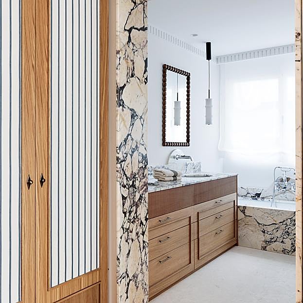 Revestimiento de piedra en bañera y marco de uno de los baños proyectado por la arquitecta.