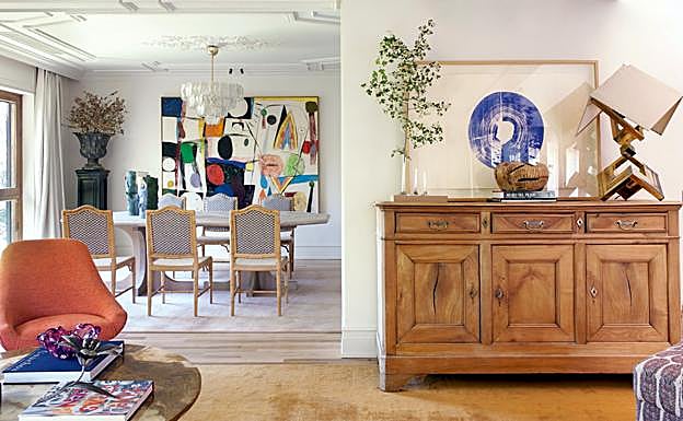 Vista del comedor desde el salón, con una silla Tulip, aparador de roble antiguo, cuadro de Guillermo Fornés y lámpara de latón art déco. En el comedor destaca la obra de Sune Christiansen.