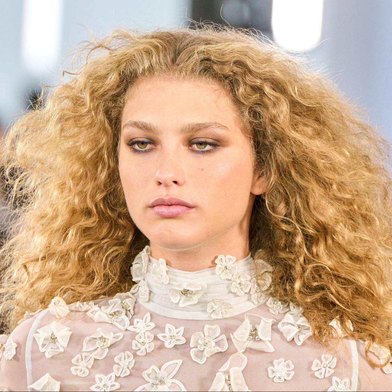 Una modelo con el pelo rizado y encrespado.