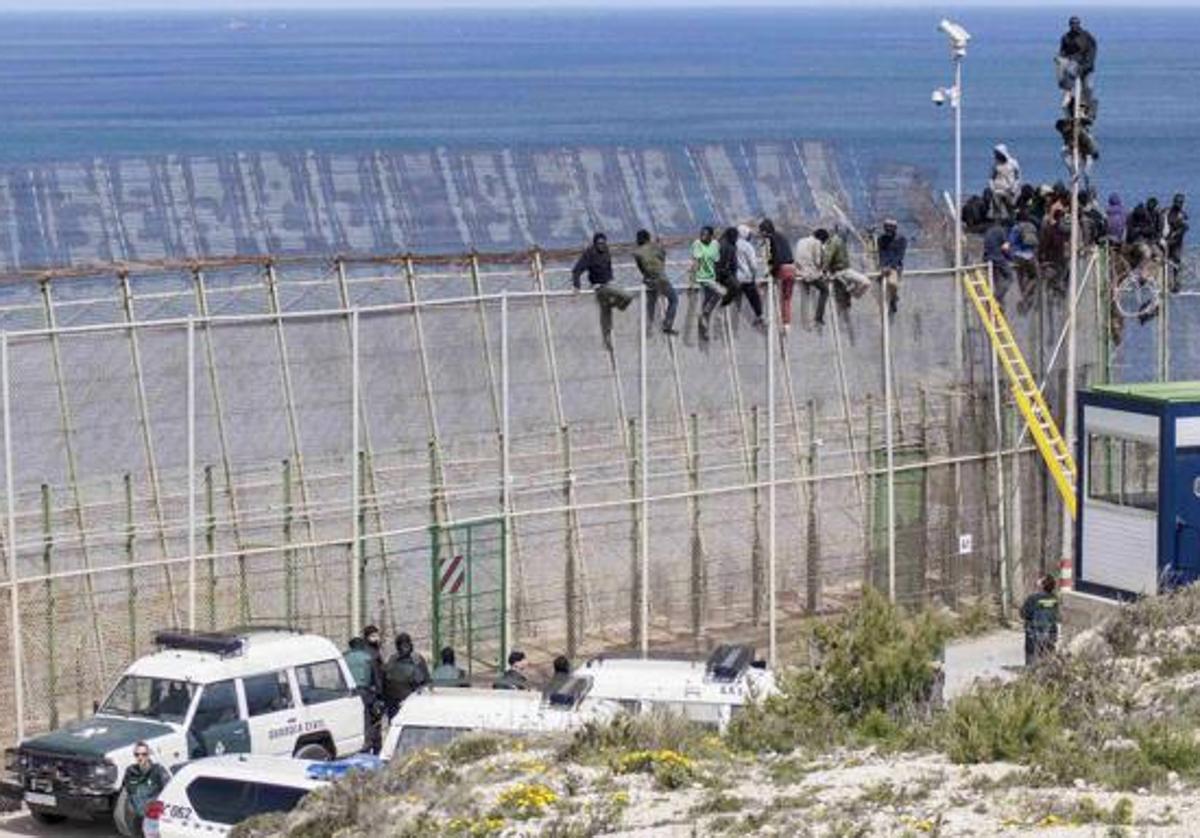 Inmigrantes encaramados a la valla de Melilla, en una imagen de archivo.