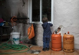 Un niño juega junto a unas bombonas de butano