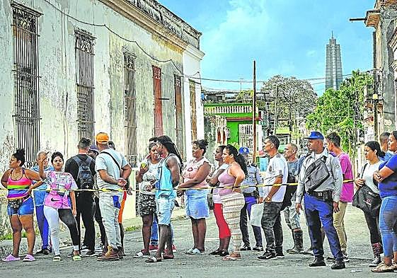 Una fila de cubanos siguen los trabajos de reparación de los daños ocasionados por el huracán 'Ian' en la localidad de El Cerro