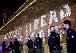Policías italianos montan guardia junto a un muro en el que se observa una pintada en favor de la puesta en libertad del anarquista Alfredo Cospito.