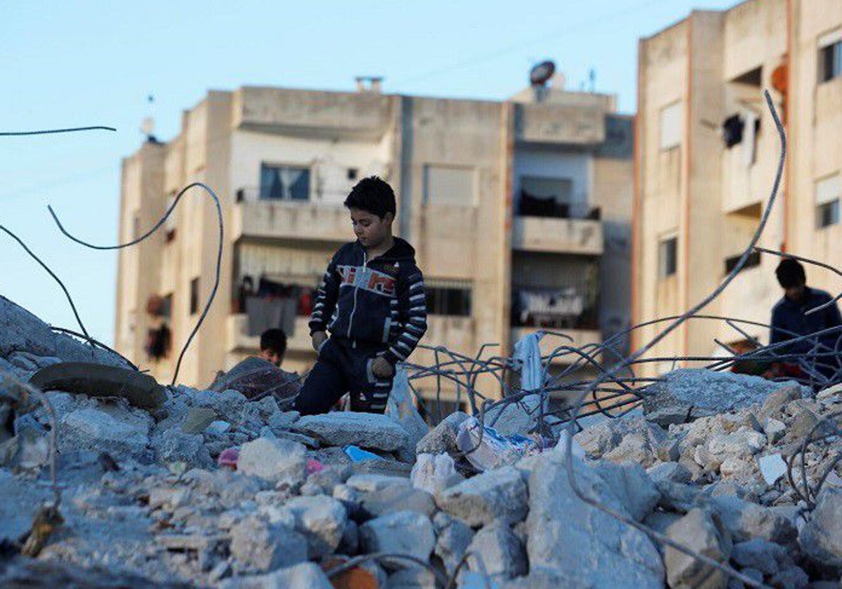 Niño sobre ruinas tras el terremoto en Siria.