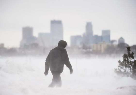 Un hombre camina en por un parque de Minneapolis durante una tormenta de nieve