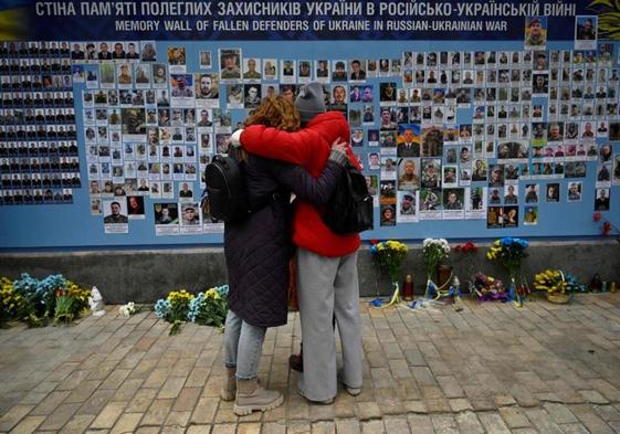 Dos mujeres observan el muro con los retratos de los fallecidos en la guerra de Ucrania