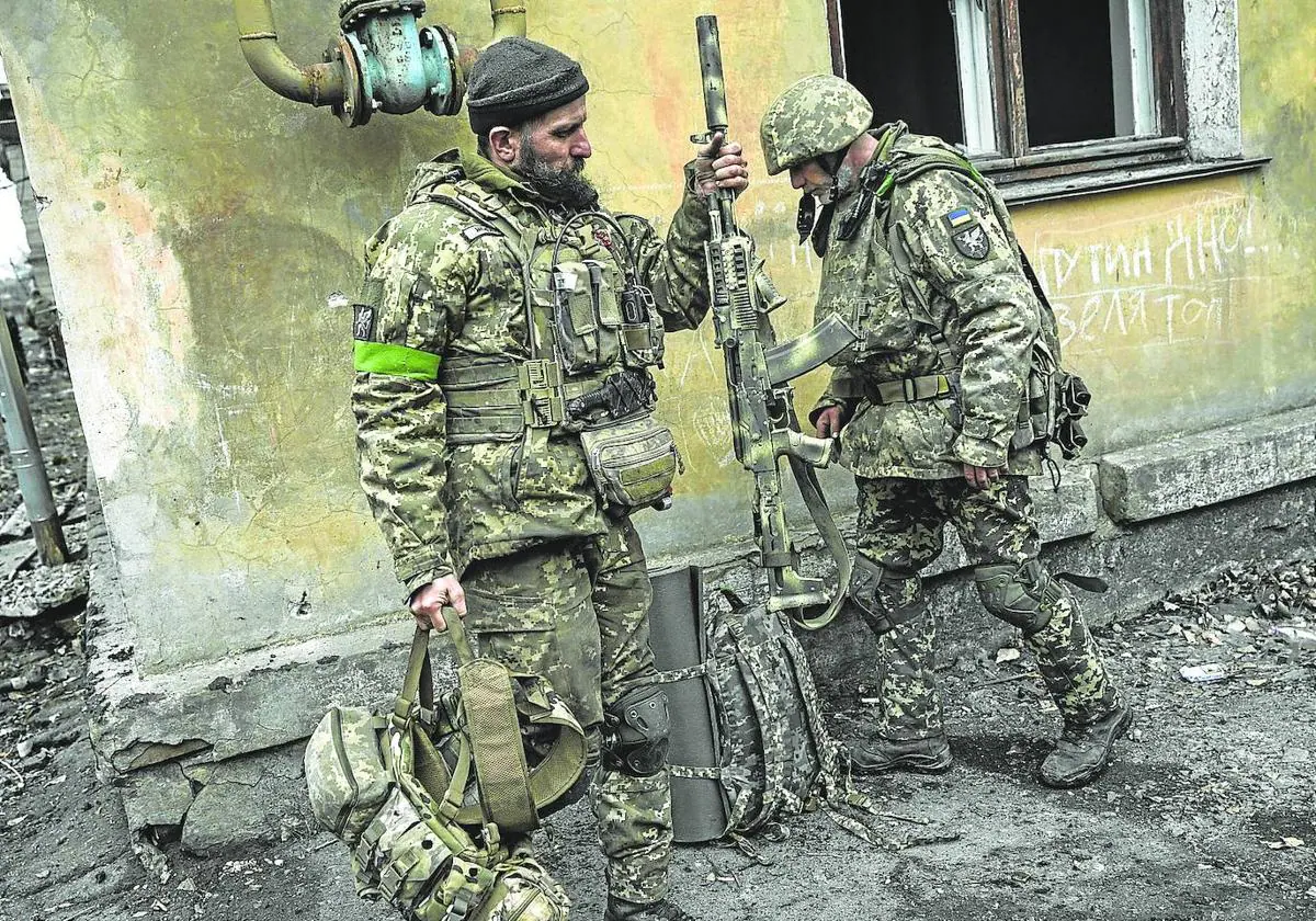 Dos soldados ucranianos desplegados en Bajmut recogen sus armas para dirigirse al frente.