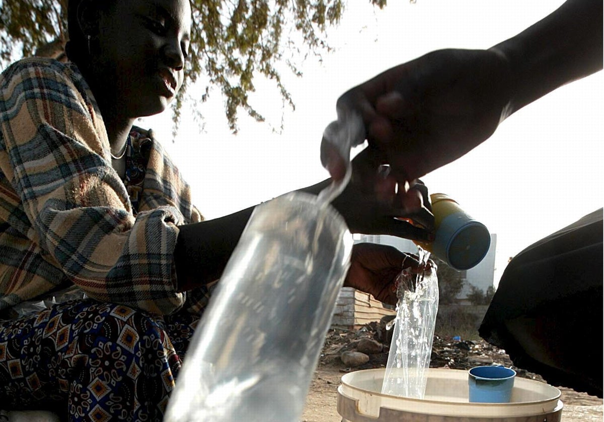 Una niña senegalesa llena unas bolsas con agua potable para venderlas al público en una tienda de una carretera de Dakar, Senegal.