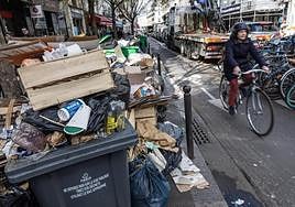 Una mujer pasa junto a contenedores rebosantes de basura tras dos semanas de huelga en París.