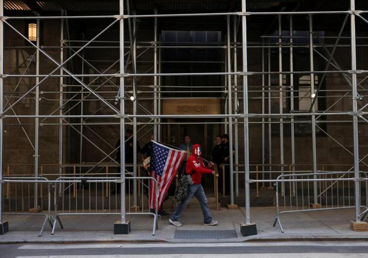 Un partidario de Trump se pasea frente al Tribunal Penal de Manhattan con una bandera estadounidense.
