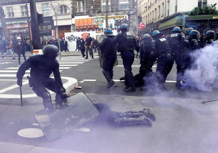Un policía protege con su escudo a un compañero que ha sido derribado por el impacto de una piedra en París.