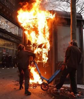 Imagen secundaria 2 - Dos radicales destrozan un escaparate durante las refriegas que tuvieron lugar en una jornada donde se repitieron los incendios y disturbios en varias ciudades francesas.