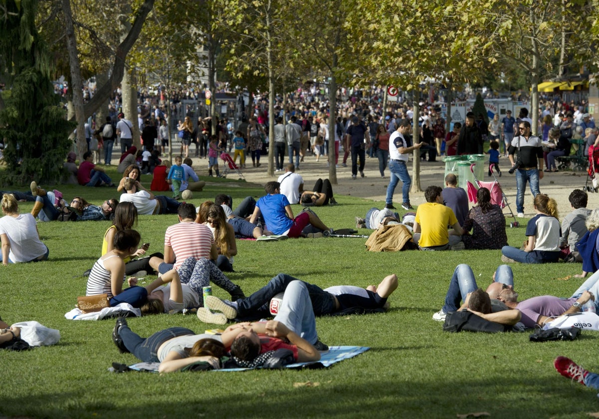 Varios grupos de ciudadanos descansan en un parque urbano.